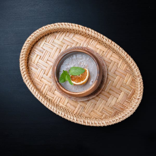 Nok's Kitchen dessert: a creamy dish with orange slice and mint on a woven tray.