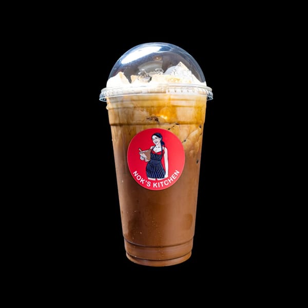 Iced coffee with cream and a Nok's Kitchen logo sticker on a black background.